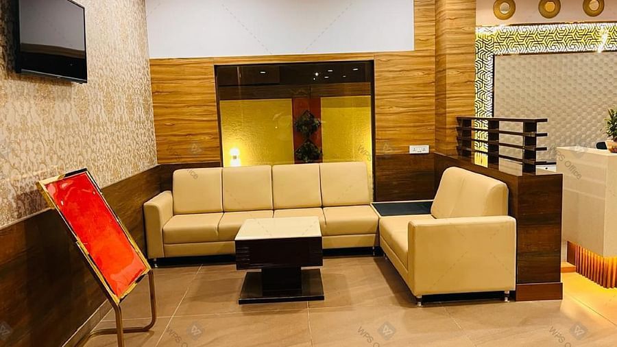 Modern lobby area with beige sofas and mounted TV at Hotel Dr Rajkumar International.