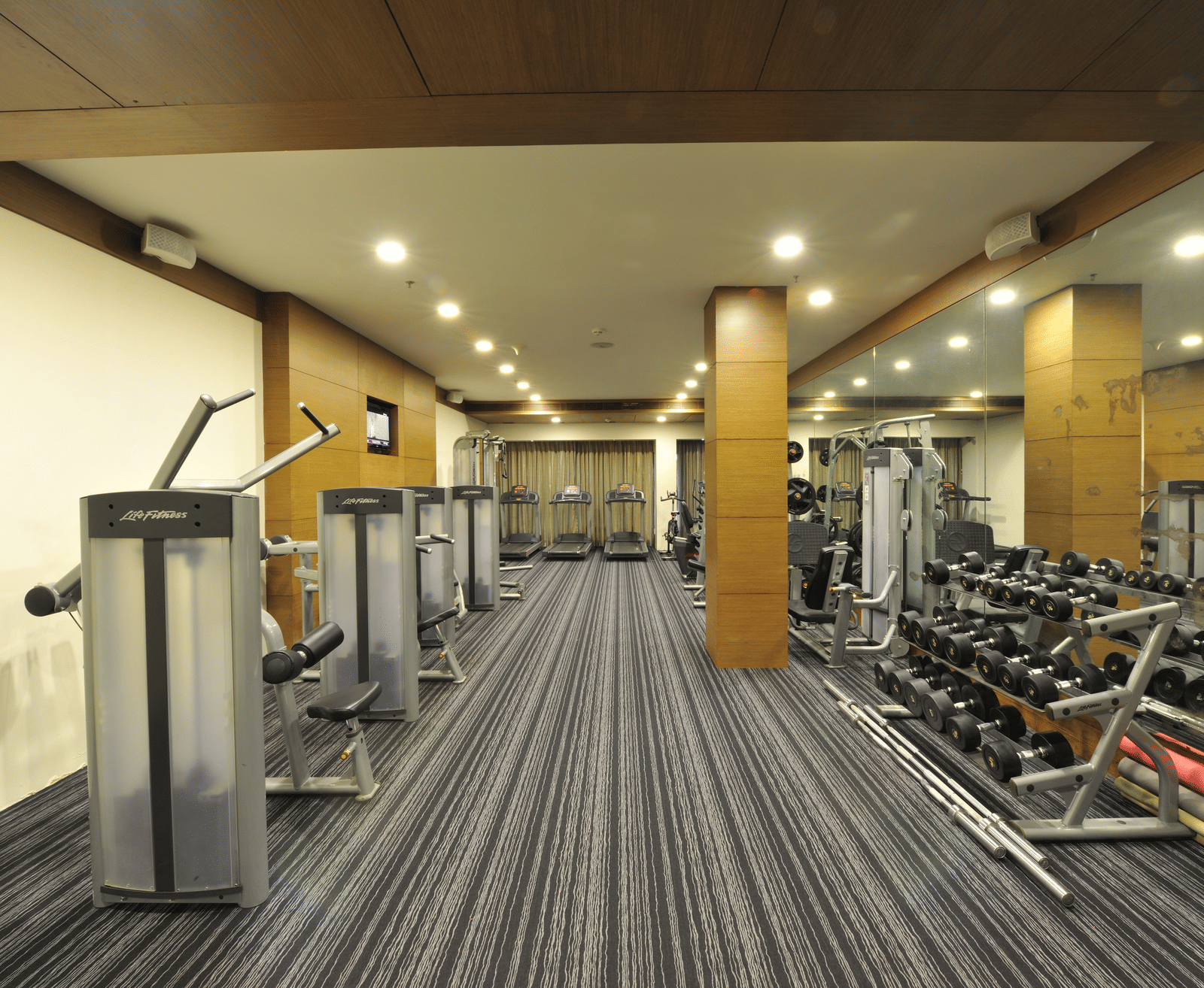 Modern gym with various workout machines and equipment at Narayani Heights Hotel & Resorts, Ahmedabad.