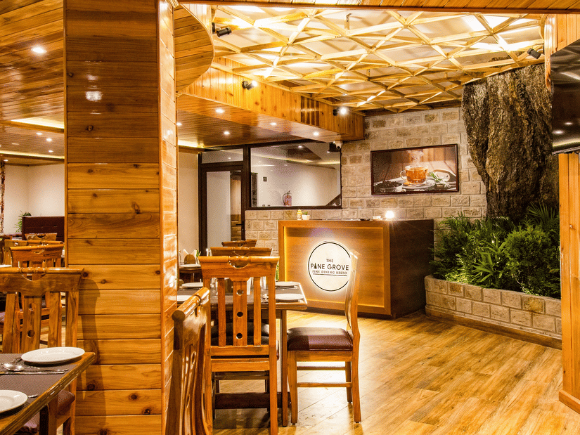 The Pine Grove Fine Dining Resto, the best restaurant in Darjeeling, featuring warm wooden interiors, cosy seating, ambient lighting, and an elegant dining setup.