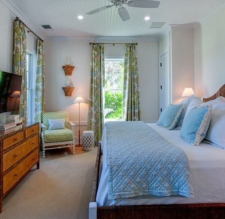 A well-appointed bedroom at Abaco Inn featuring a large bed featuring a headboard, bedside tables with lamps, and a television mounted on a dresser 