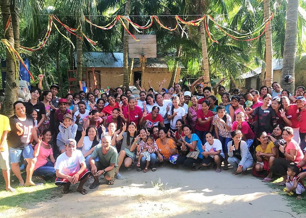 Large group of people seated outdoors under trees for a group photo at Flower Island Resort.
