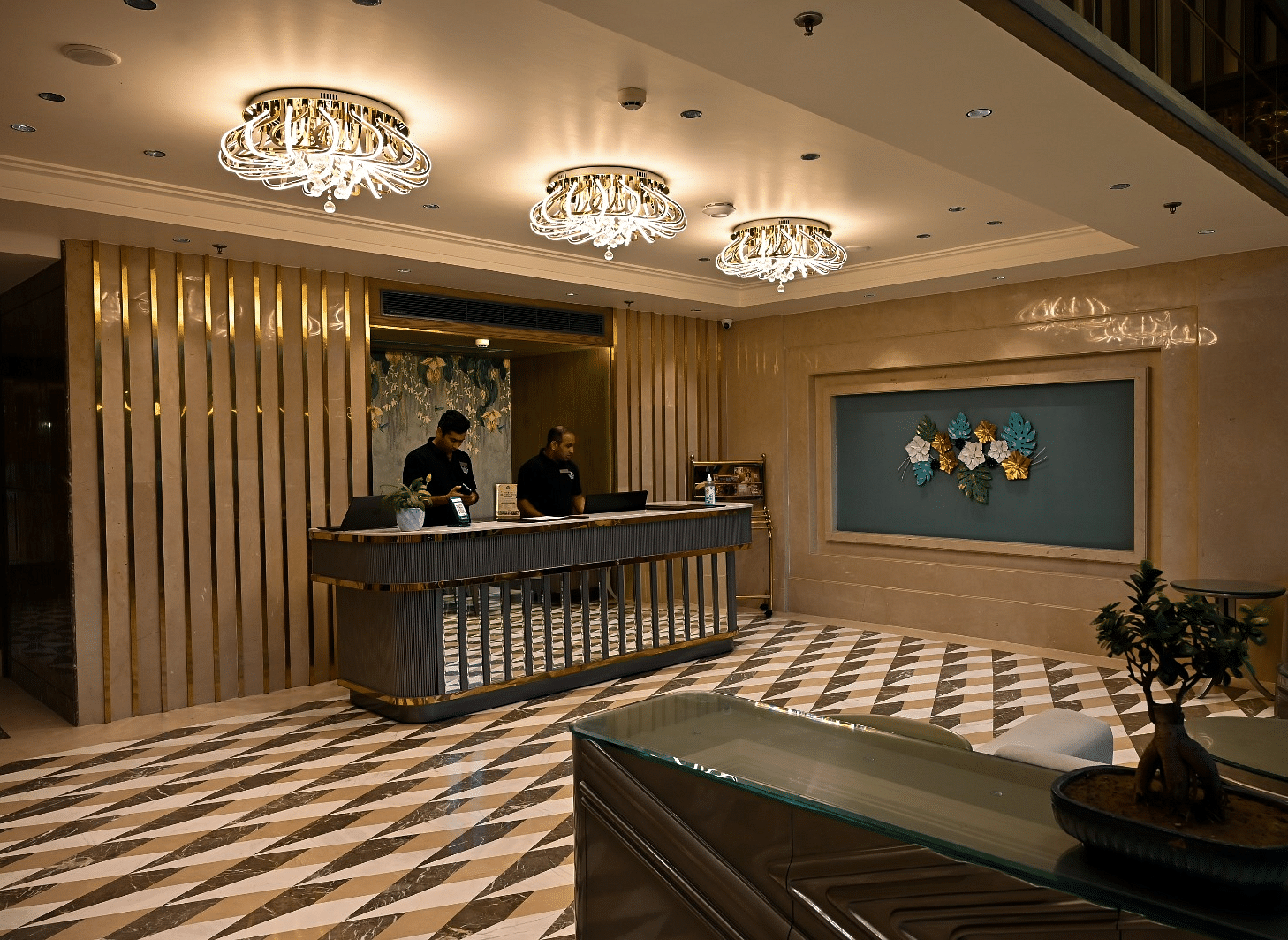 Reception area featuring a front desk with an individual assisting, illuminated by hanging ceiling lights at BluSalzz Residence, Amritsar.