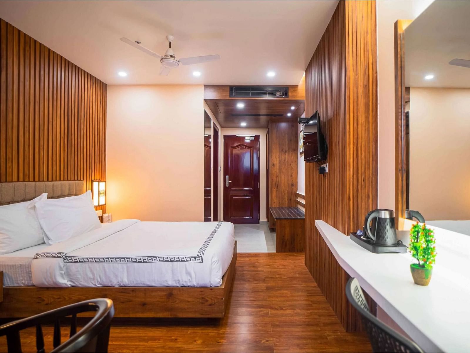 A well-furnished room at Mansha Palace offers a comfortable bed, wooden walls, a mirror, and a beverage station.