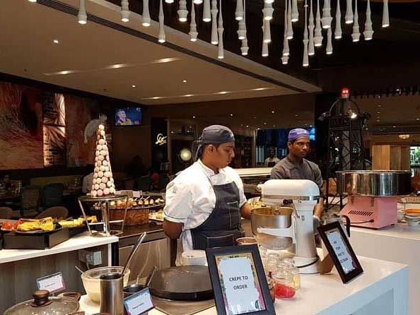 A buffet with various food items with servers in the background.