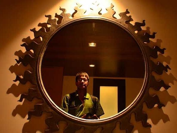 A person standing in front of a mirror, gazing at his reflection.