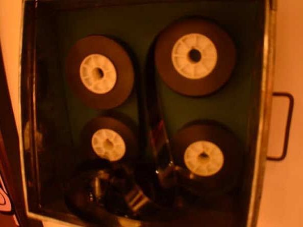 An image showing a neatly arranged stack of vintage film rollers.