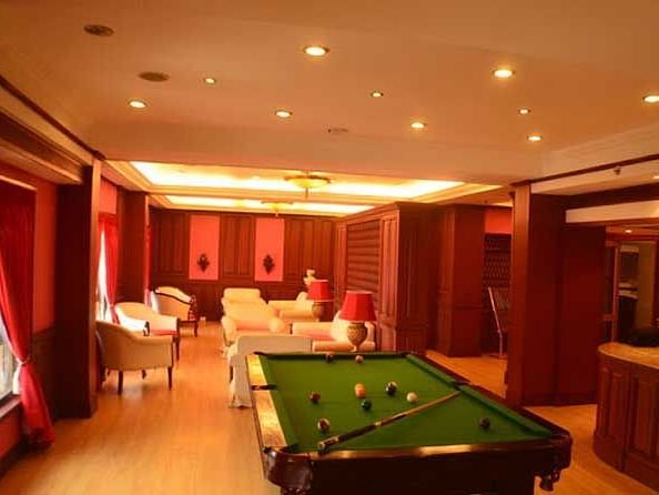 An image of a pool table placed in a room which also features sofa sets and other furniture