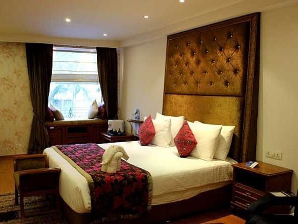 An image of a bedroom with a bed, bed side tables, couch and an expansive window