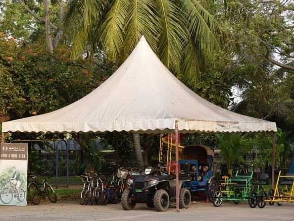 A semi tent which has a jeep, pulling rickshaws and a lot of bicycles with trees in the background.