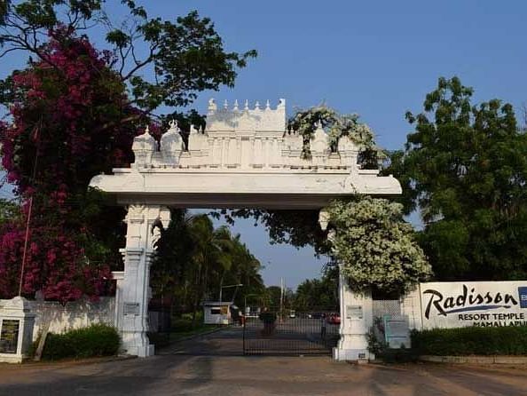 View of a white arch entrance to Radisson Blu resort temple bay mamallapuram surrounded by trees 