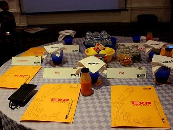 An image of a round table laid out with booklets, pens, juice bottles, and much more