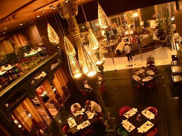 An image of a restaurant with seating arrangement and warm decorative lighting hanging from the ceiling