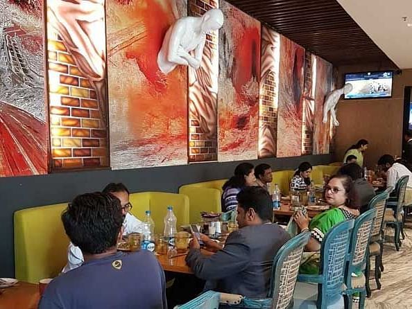 A view of a hall where a lot of people are eating on different tables.