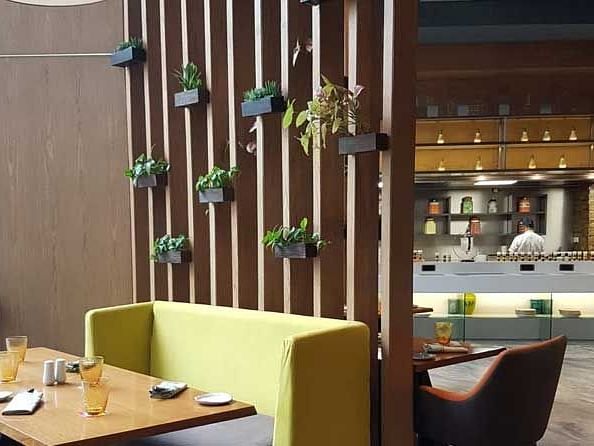 Aesthetic view of a room consisting different seating arrangements with a wall decorated with plants.