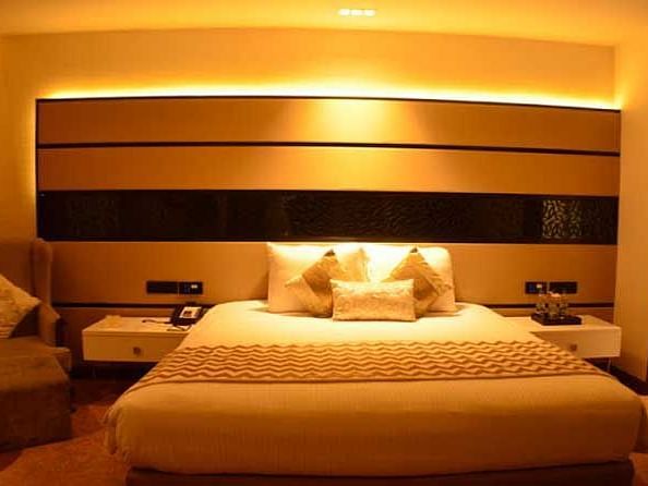 A bedroom featuring fancy beadboard lighting with warm yellow light and a table with water bottles.