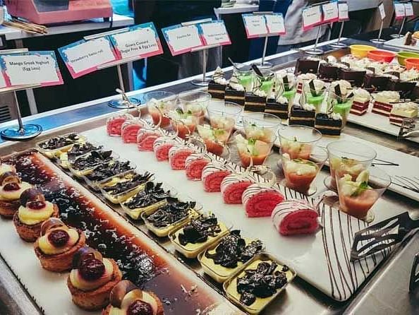 A view of the various desserts arranged in a aesthetic way in a buffet.
