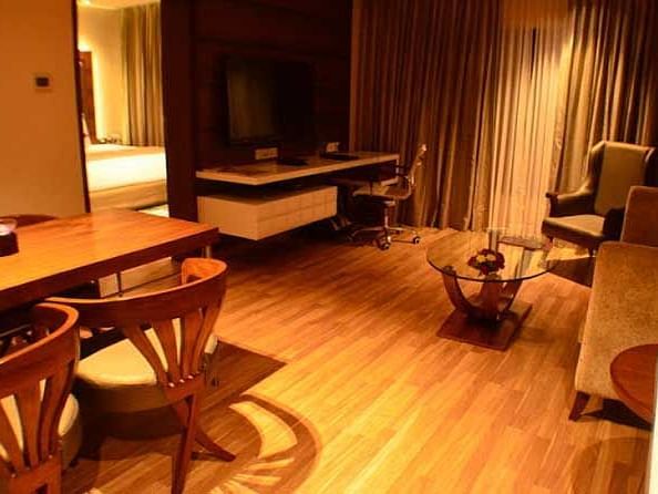 An image of a room featuring a sofa set, a table, a work desk and chair, flat screen TV, and a dining table