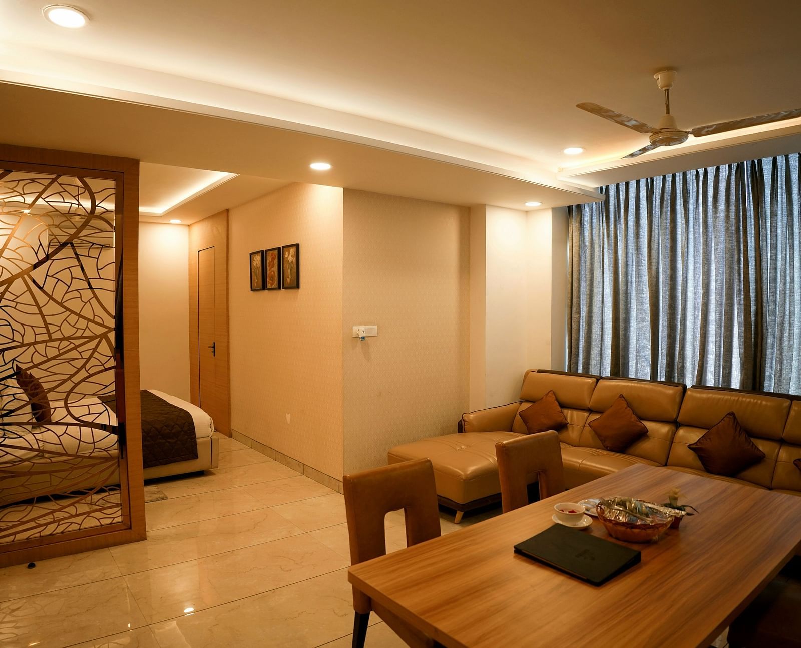 A spacious living room with a sectional sofa and decorative partition leading to another room - TGI Insignia, Bhopal