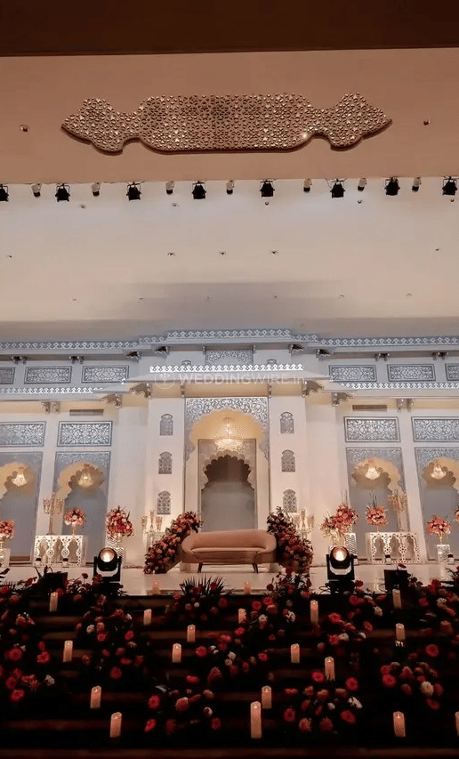 A large white palace building with lit windows and guests seated outside on the lawn at Beelwa Palace, Jaipur.