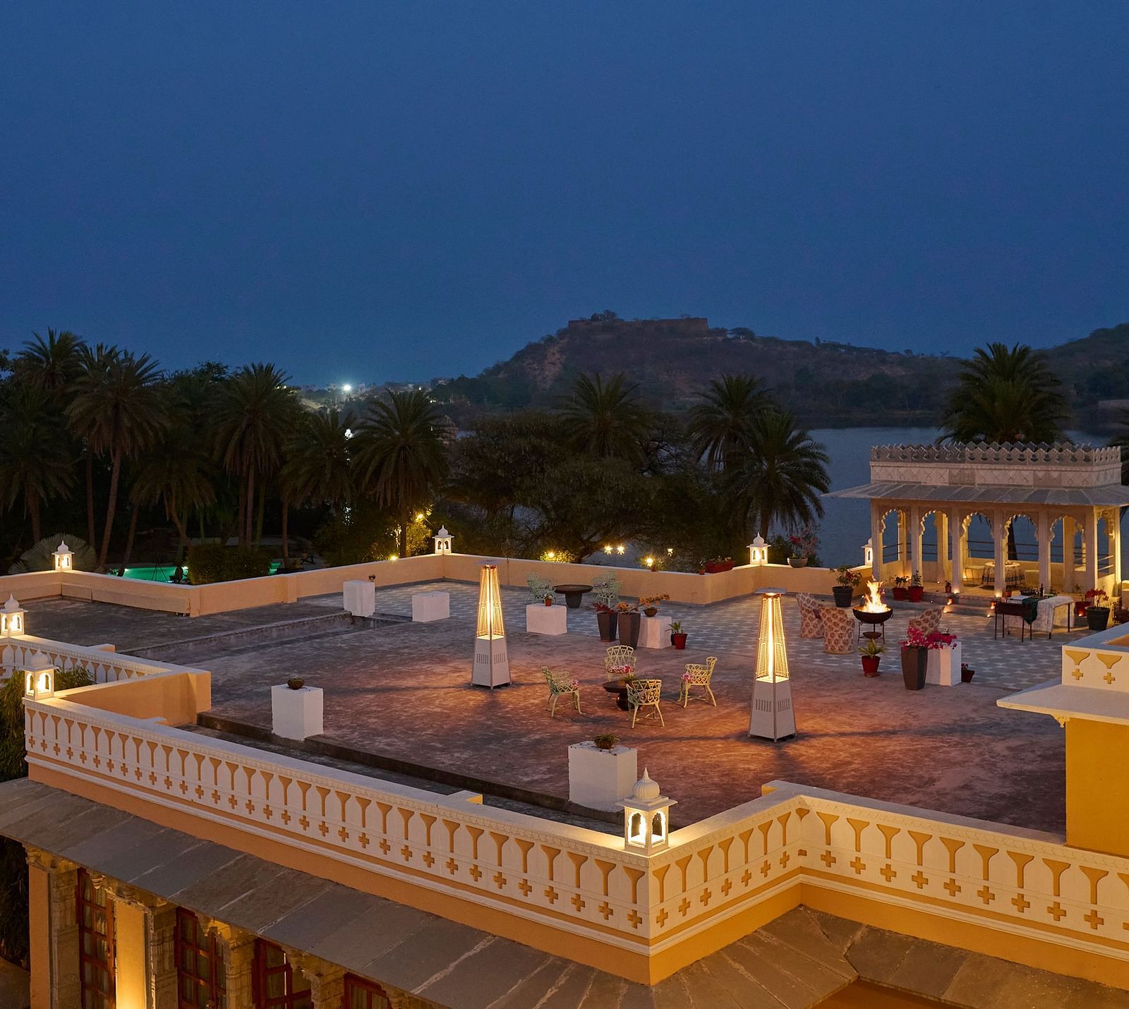 image of the terrace at dev shree, deogarh at a night time overlooking the a lake in front of the facade