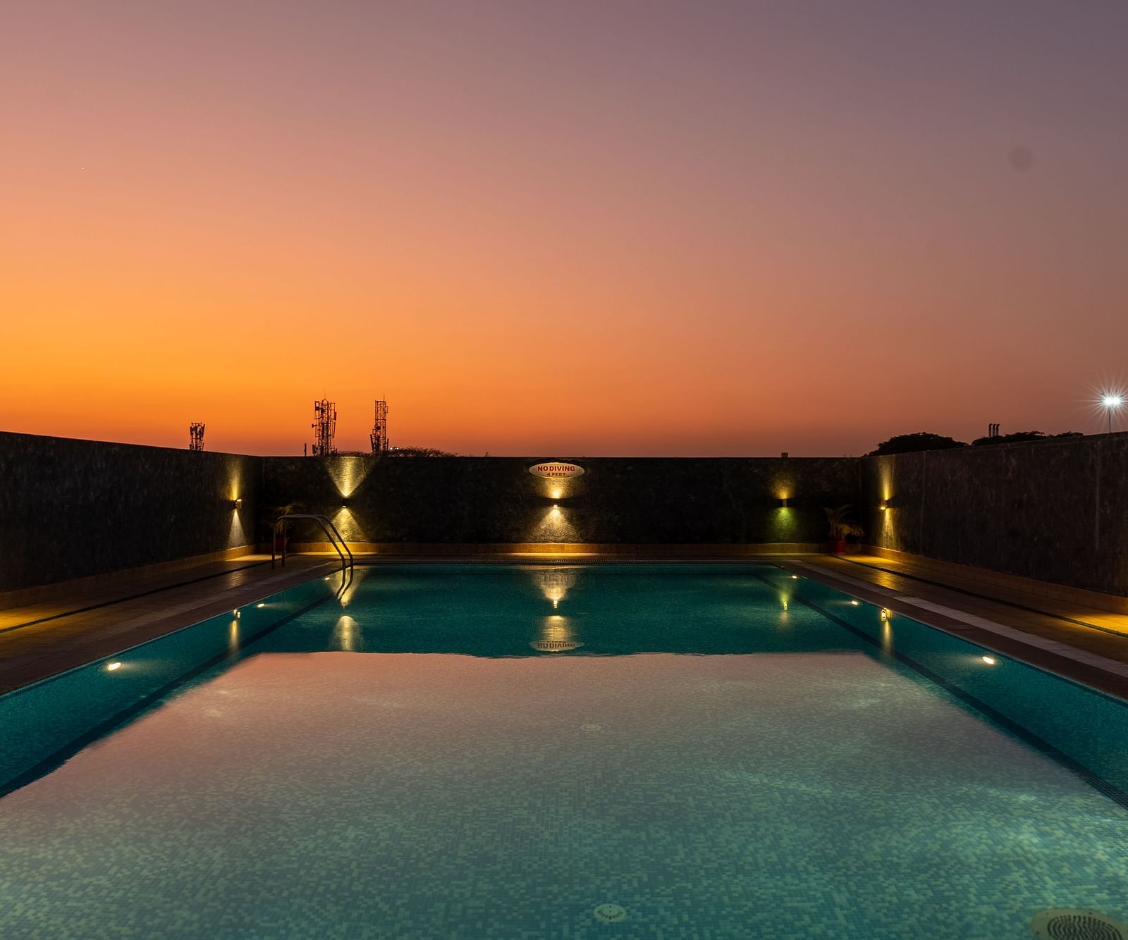 An image of an outdoor swimming pool installed with dim lights on the sides of it - Hotel Pai Vista, Mysore