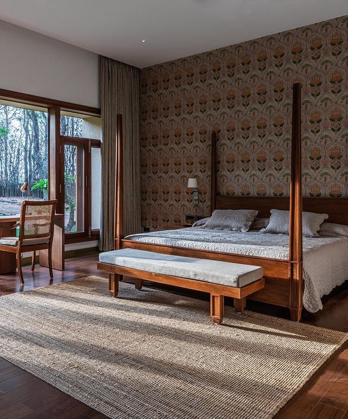 A bedroom with a four-poster bed, large windows, and a brick wall, modern design - Shreyas Retreat