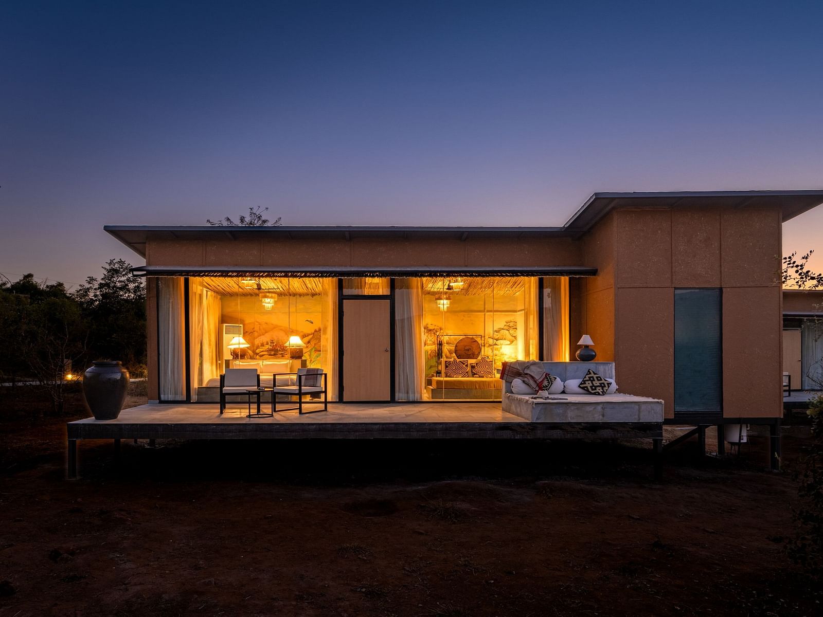 A facade image of a room with bright lighting and greenery around - Utsav Camp Sariska.