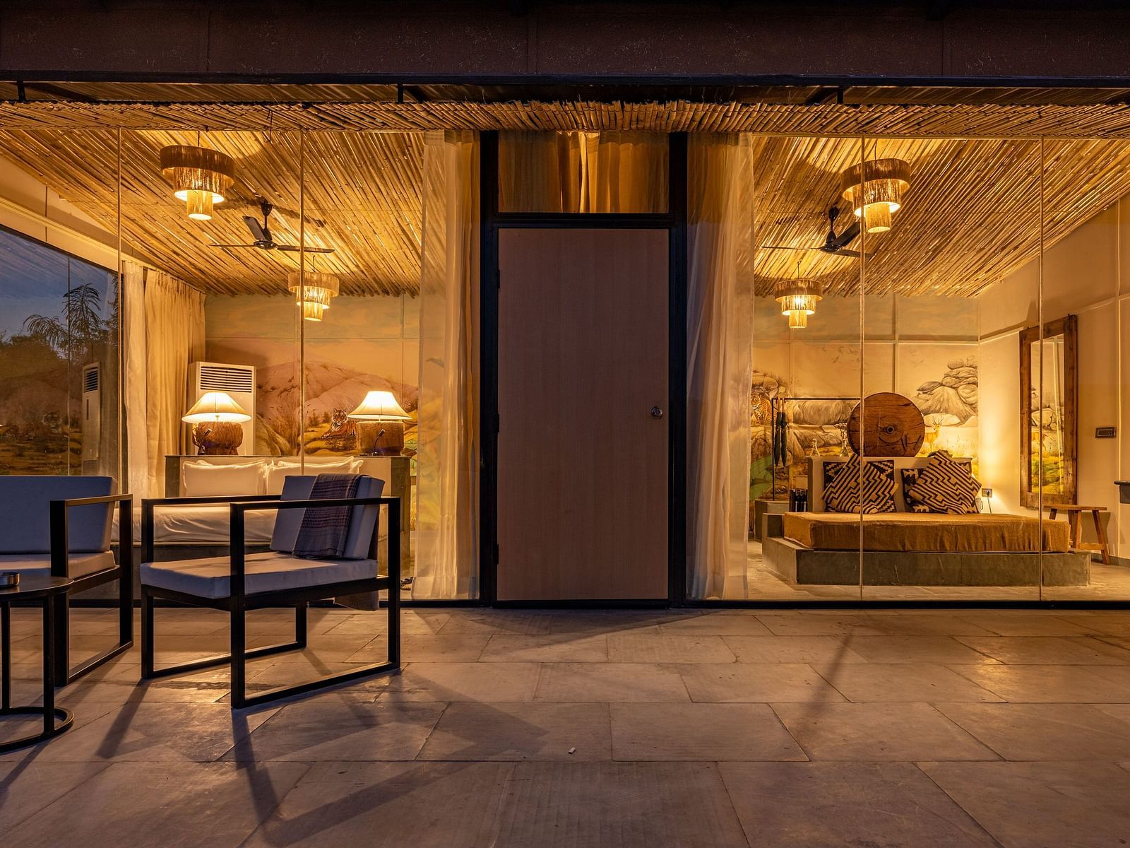 A facade image of a room with bright decorative lighting with outdoor seating arrangement - Utsav Camp Sariska