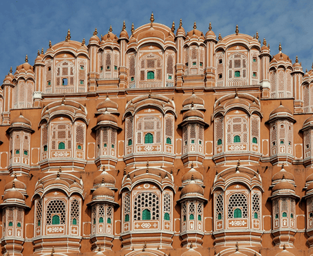 The intricate, pink sandstone facade of the iconic Hawa Mahal stands grandly against a bright sky.