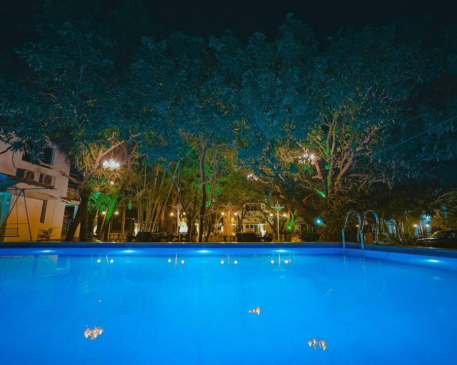 An image of a Swiming Pool with having some trees around and a building at Rangamati Garden Resort
