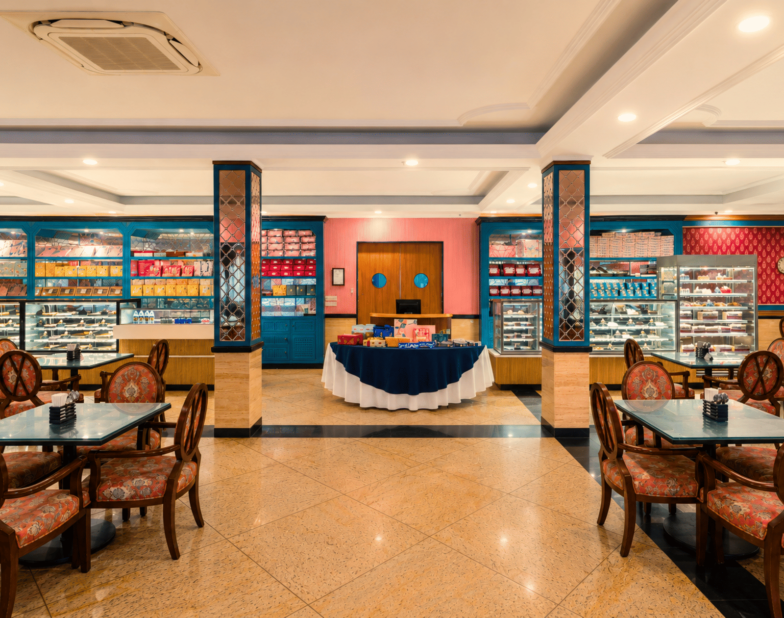 Bakery and confectionery shop with glass display counters, shelves of gift boxes and cafe tables and chairs at MAYFAIR Oasis Resort & Convention, Jharsuguda.