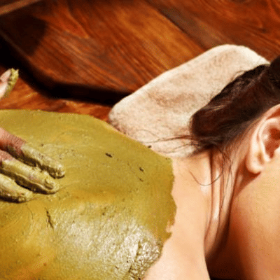 A practitioner applies a substance on the back of a person lying on a surface at YO1 Longevity & Health Resorts