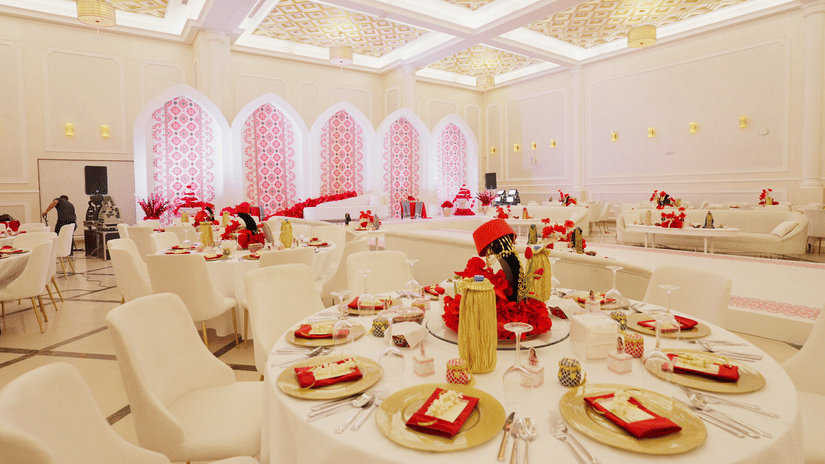 An elegantly decorated banquet hall at La Maison, Doha, with round tables set for a formal event.