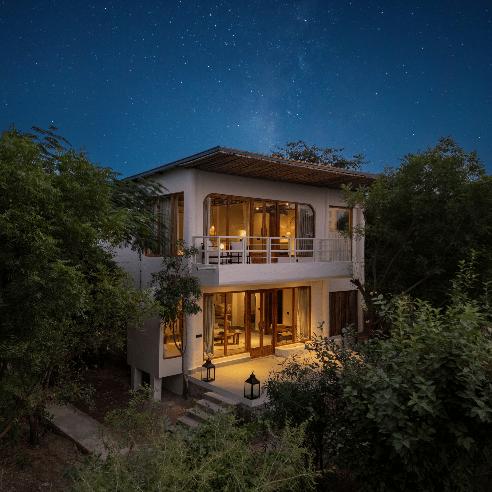 Exterior of a modern two-story villa surrounded by trees and plants.