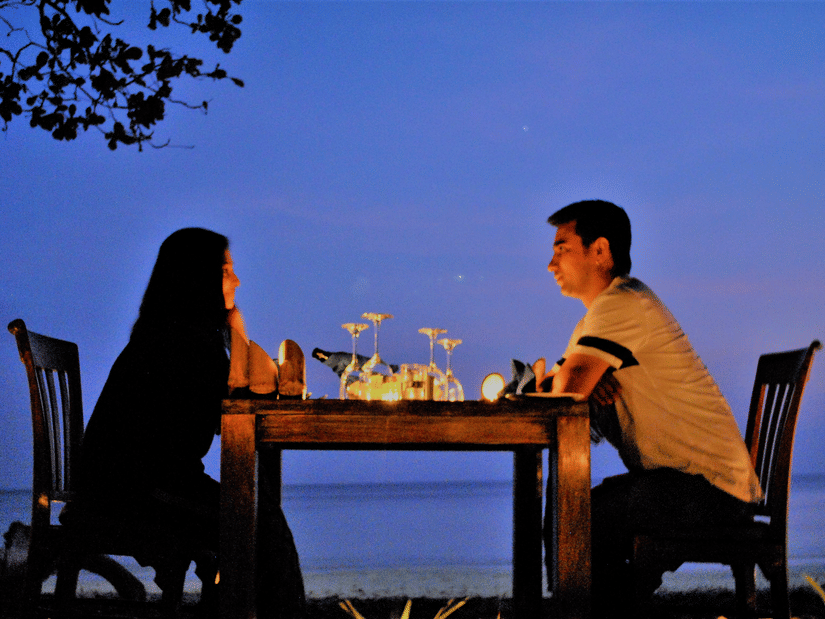 A couple outside enjoying a candlelight dinner by the beach