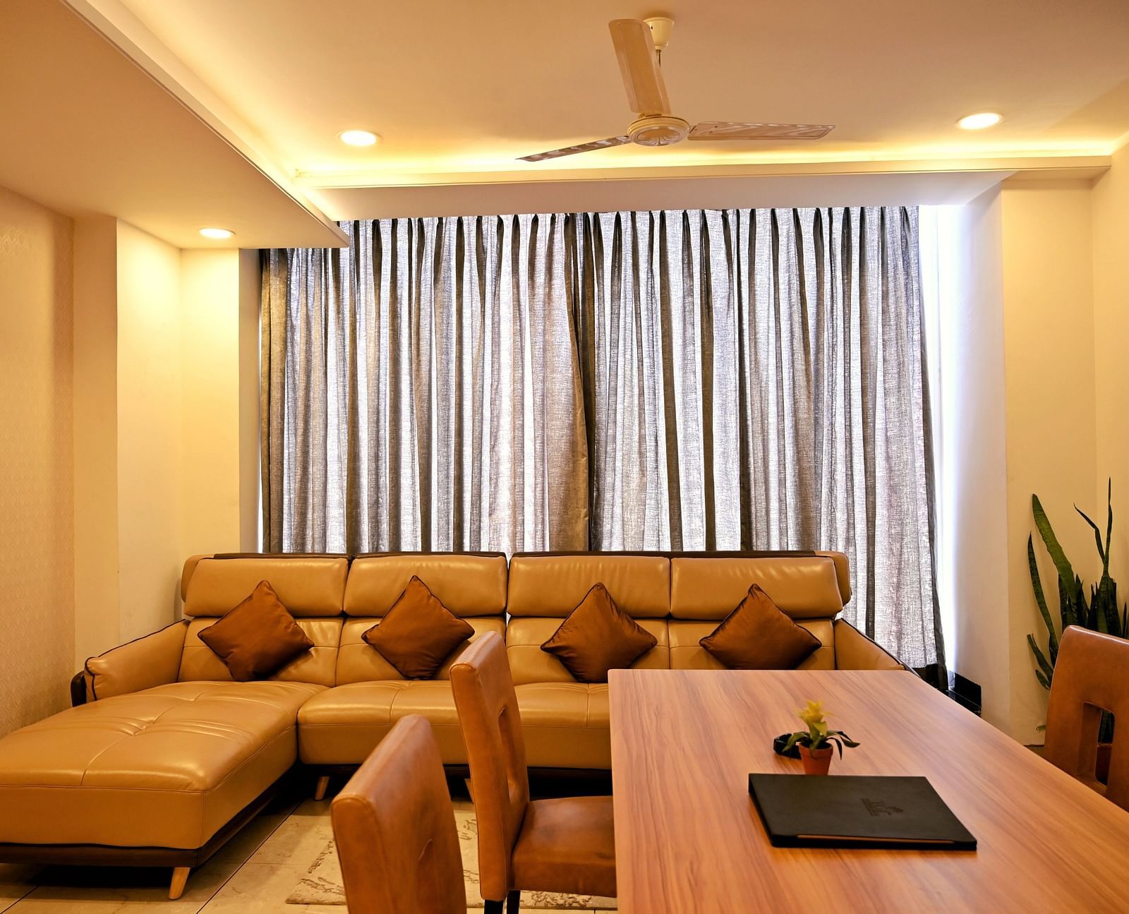 A cosy living room with a large beige sofa and a wooden floor - TGI Insignia, Bhopal
