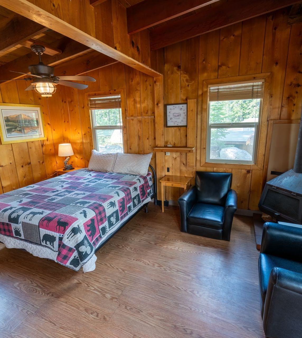 Spacious cabin bedroom with floral bedding, armchairs, and natural wood walls at Kit Carson Lodge.