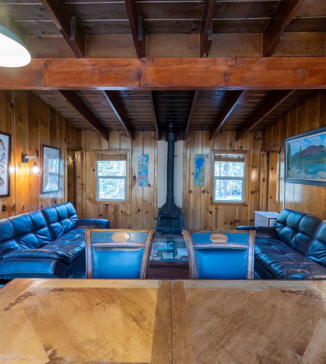 Cozy wooden dining and living area with blue couches and large table inside a rustic cabin at Kit Carson Lodge.