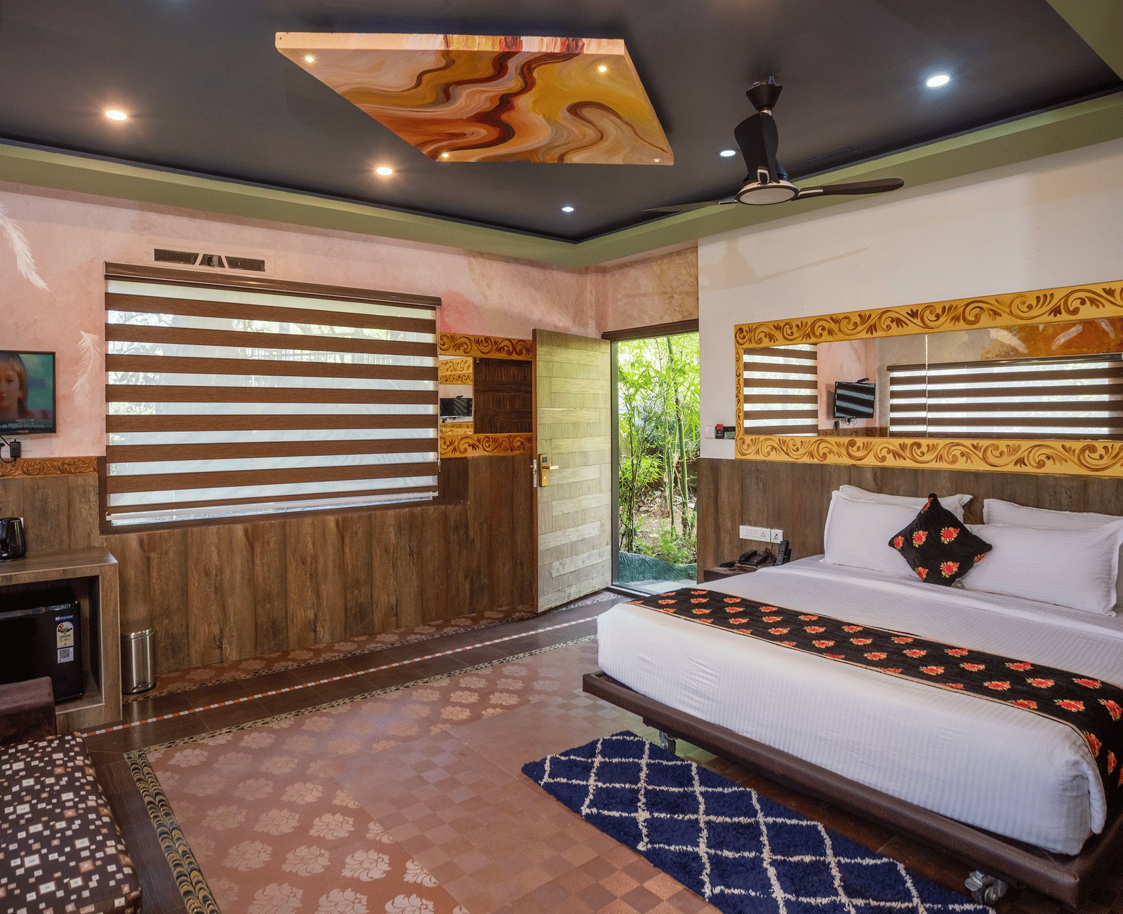 The sleeping area of the Jungle Room at Parakkat Nature Hotel and Resorts, Munnar, featuring a large bed, decorative wall art, and a reflective ceiling panel.