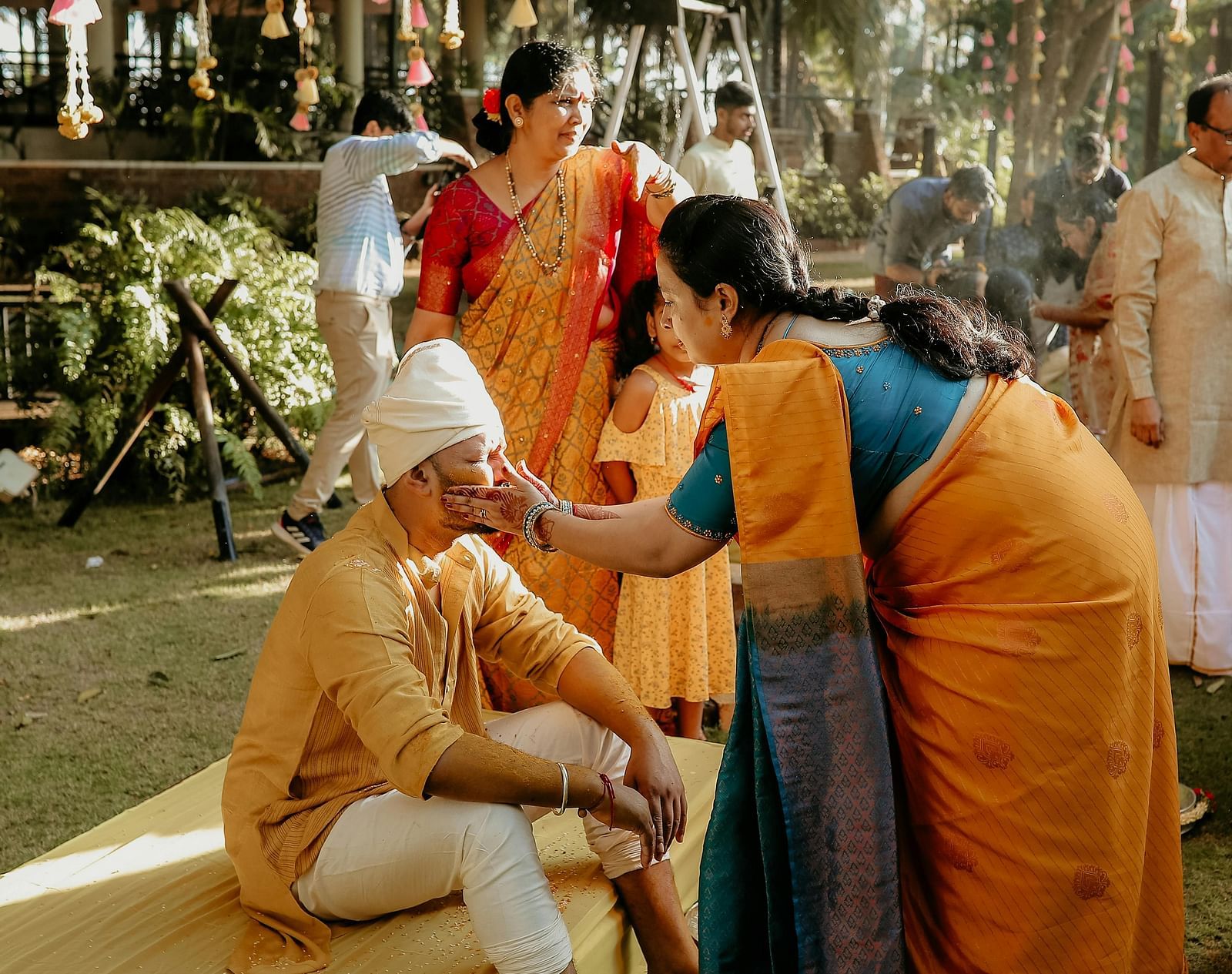 image of a middle aged woman applying haldi to the groom