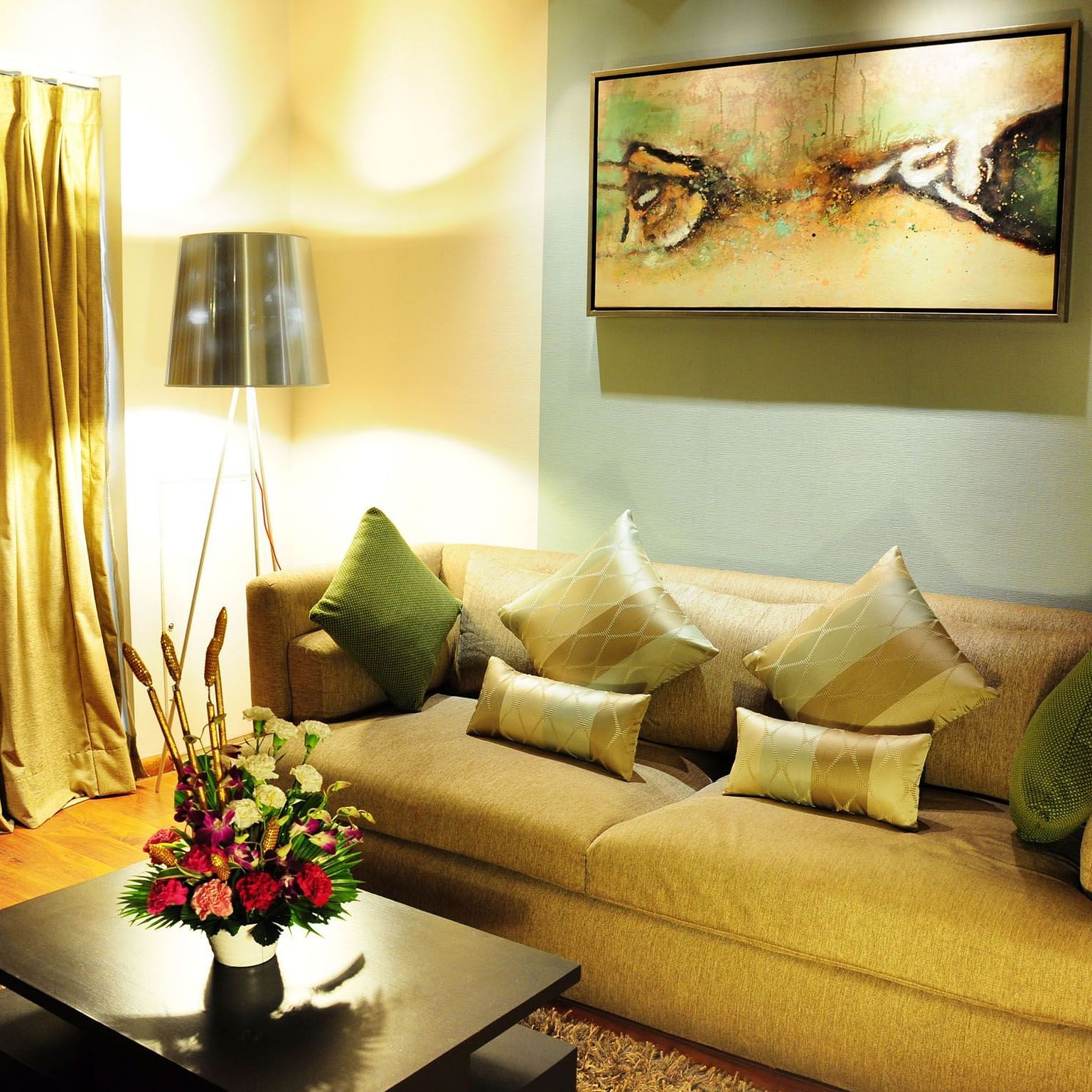 A comfortable couch with cushions arranged on it with a tall lamp brightly illuminating the living area of the Premier Suite - Senses Hotel