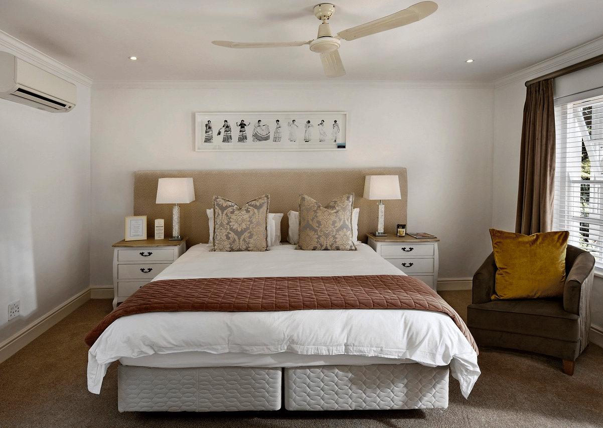 A double bed with a ceiling fan hanging over it in a bedroom.