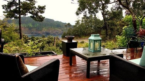 A deck with couches, a teapoy and surrounded by lush greenery - Brewery Gulch Inn & Spa