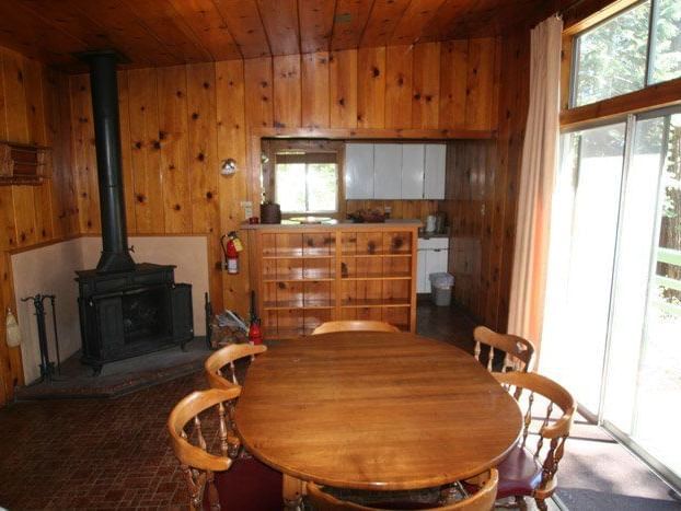 The interior of a rustic cabin features wood-paneled walls, a round dining table, and a fireplace | Polar Bear