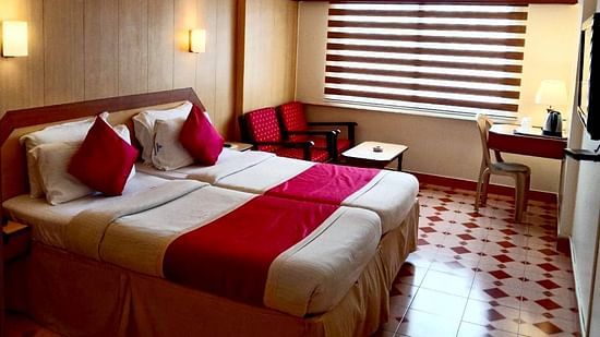 Room with double bed, seating space, a work station, a mini bar, and a wall-mounted TV at Hotel Swagath, Bangalore