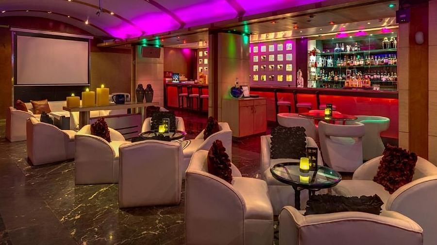 Chic lounge bar with vibrant lighting, plush seating, and a well-stocked bar – Hotel Hindusthan International, Kolkata.
