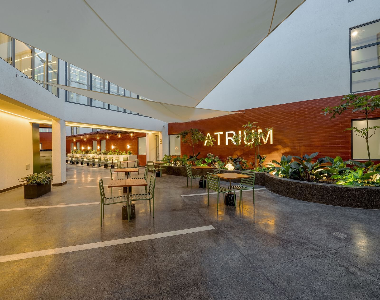 A modern outdoor seating area with a large, red 'ATRIUM' sign on the wall.  - The Pelican Hotel, Accra