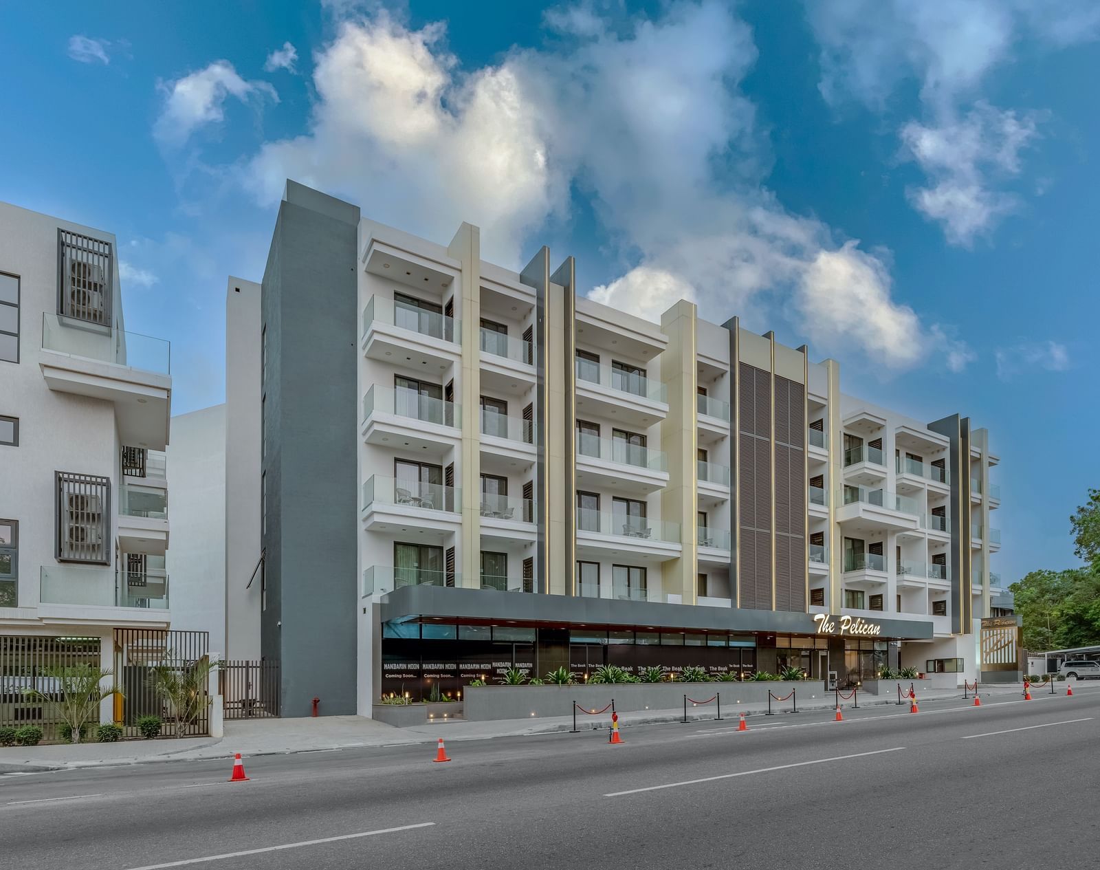 A multi-story hotel building with a covered walkway and a street in front. - The Pelican Hotel, Accra