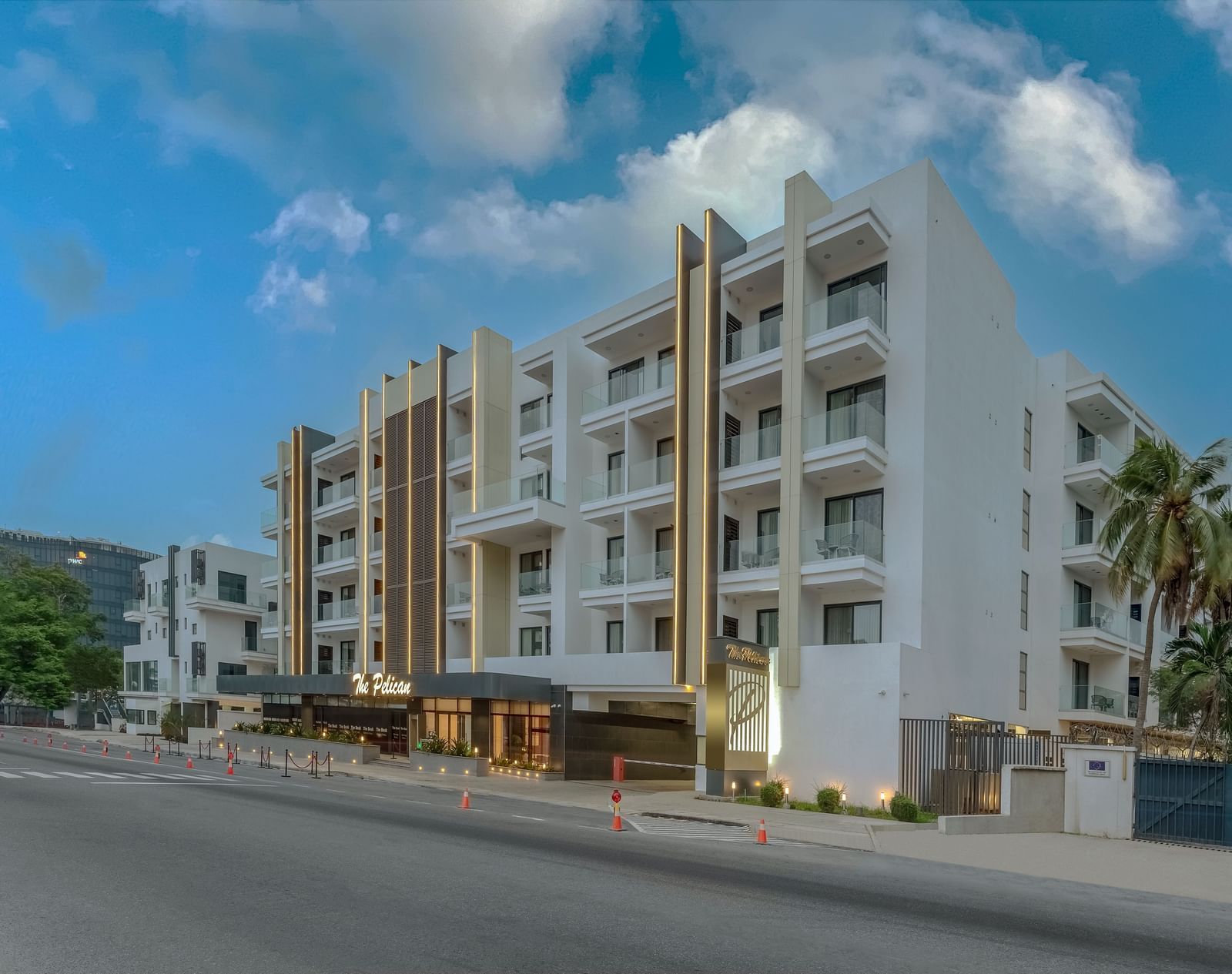 A rendering of a white two-story hotel with palm trees and a blue sky in the background. - The Pelican Hotel, Accra