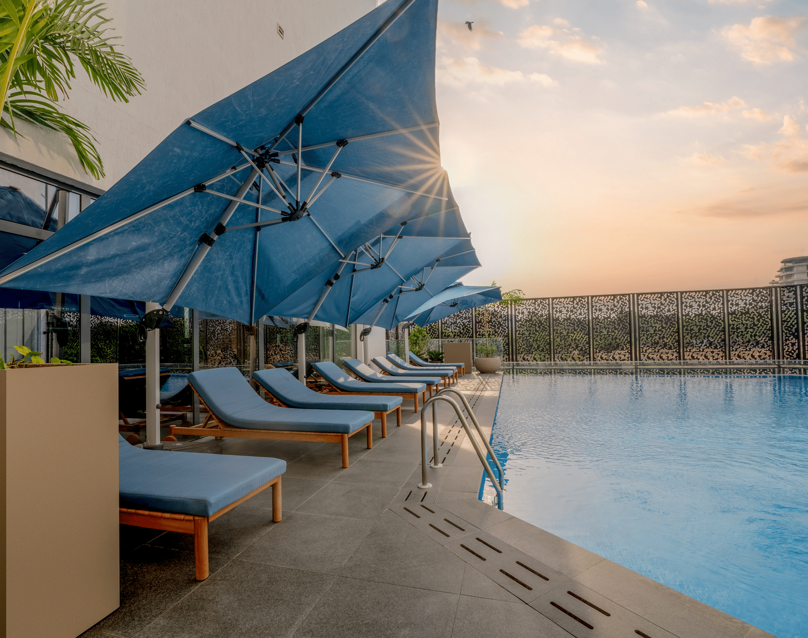 A pristine swimming pool, one of the best amenities at hotel in accra, glistens under a warm sunset sky, inviting a refreshing dip. - The Pelican Hotel, Accra